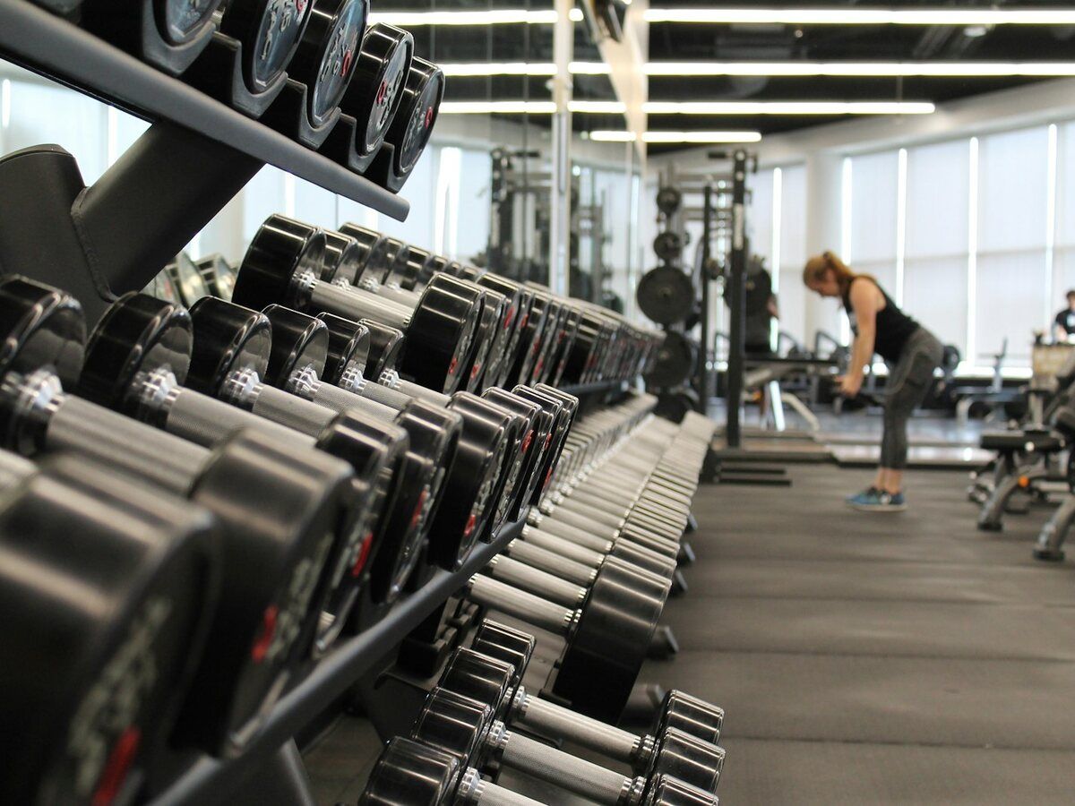 Sala de gimnasio con mancuernas ordenadas y máquinas de entrenamiento