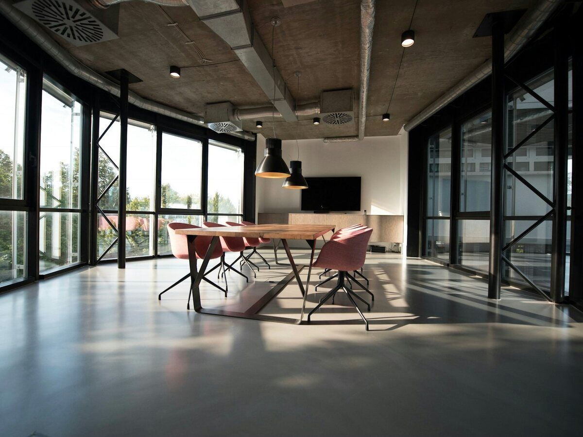 Oficina diáfana y moderna con mesa de reuniones y grandes ventanales